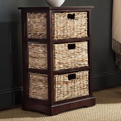 an empty white vase sitting on top of a wicker basket next to a black cabinet