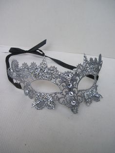 * This stiff silver lace half mask has been designed with five pointed silver beaded stars which have been trimmed and stationed around each eye. Down the front of the mask four faceted crystals accent the shape of the nose. * To secure the mask there are two black satin ribbons on each side to be tied in the back. * A great piece for a Masked Ball, a Night at the Opera, Class Reunion, Birthday Celebration, Halloween, New Year's Celebrations, Parade or Festival, Costume party or Play, Carnivale, Mascarade Ball Dresses, Masquerade Half Mask, Mascarade Dresses, Masquerade Party Themes, Masquerade Mask Black, Silver Masquerade Mask, Beaded Stars, Night At The Opera, Masquerade Theme