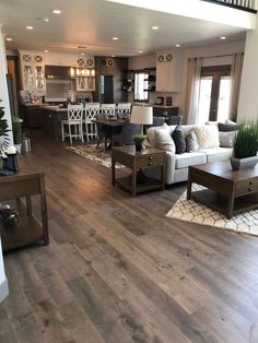 a living room filled with furniture next to a kitchen and dining room table on top of a hard wood floor