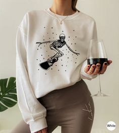 "Ski Sweatshirt, Skeleton Snowboard Shirt, Apres Ski Sweatshirt For Women, Womens Ski Gift, Gift For Ski Lover, Ski Season Sweatshirt, DC6385 H O W  TO  O R D E R 1️⃣Please, check and review all the photos. 2️⃣ Choose your T-shirt size and color. 🔵Different styles of shirts may have different shades of same color choice due to different manufacturer brands. 🔵For this reason, we recommend you to match shirts from the same styles if you want precisely matching colors (ex. Unisex, V-necks, Toddle Ski Apparel, Ski Tshirt Design, Ski Graphic Tee, Skiing Sweatshirt, Ski Print Sweater, Casual Crew Neck T-shirt For Snowboarding, Ski Shirts, V Neck Shirts, Ski Gifts