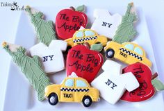 decorated cookies in the shape of taxis and apple trees on a white plate with i love new york written on them