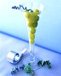 a glass filled with green grapes next to scissors