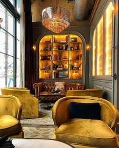 a living room filled with lots of furniture next to a tall book shelf covered in books