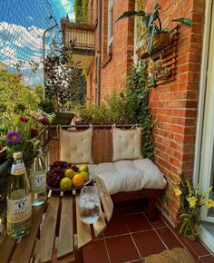 a wooden bench sitting on top of a brick floor next to a window filled with flowers