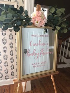 a baby shower sign with flowers and greenery in front of a mirror that reads welcome to charlotte's baby shower