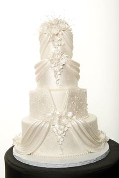 a three tiered white wedding cake on a black stand