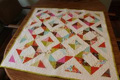 a table with a quilt on it that is sitting on top of a wooden table