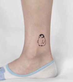 a small penguin tattoo on the ankle, with an image of a penguin behind it