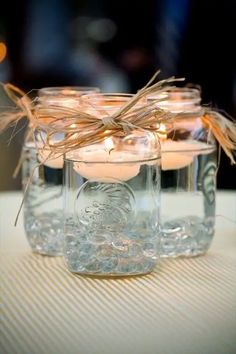 a glass jar filled with candles on top of a table next to a cell phone