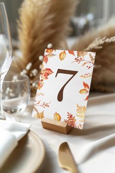 the table is set with an autumn themed place card holder and silverware in front of it