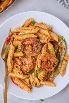 pasta with shrimp and green beans on a white plate next to a bowl of french fries