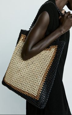 a woman is holding a large woven bag