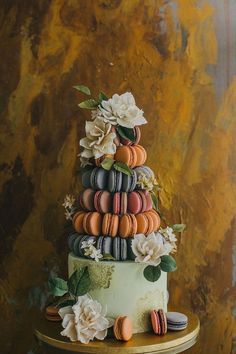 a three tiered cake decorated with macaroons and flowers