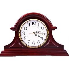 a small wooden clock with roman numerals on the face and hands, sitting in front of a white background