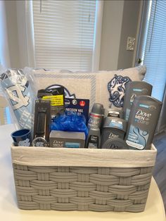 a gray basket filled with personal care items on top of a white table next to a window