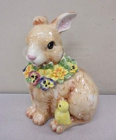 a ceramic rabbit figurine with a chickling on it's back legs