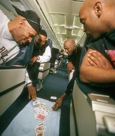 three men playing cards on an airplane