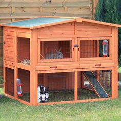 a large wooden rabbit house with two rabbits in it's cage and one on the ground