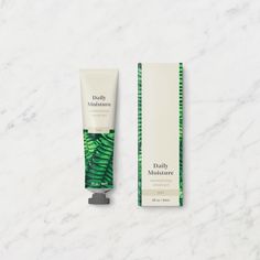 a tube of daily moisturizer sitting next to a box on a marble surface