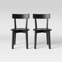 two black chairs sitting next to each other on a white surface with one chair facing the other