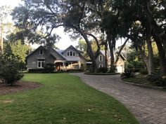 a large house with lots of trees in the front yard and walkway leading to it