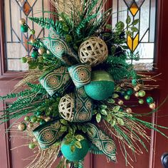 a green and gold christmas wreath hanging on the front door