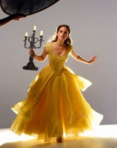 a woman in a yellow dress holding a candelabra