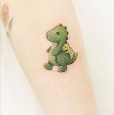 a small green dinosaur tattoo on the right leg, with a little alligator in it's lap