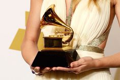 a woman in a white dress holding an award for best female pop vocal performance at the 59th annual golden globe awards