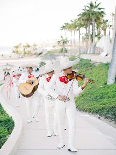 a group of people that are playing instruments on the sidewalk in front of some grass