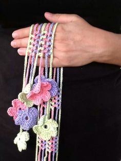 a woman is holding several crocheted bracelets with flowers on them and beads attached to the wrist