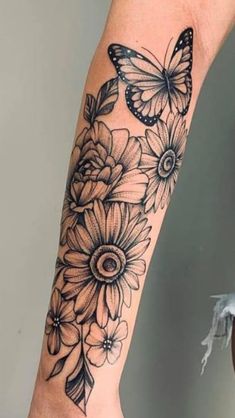 a woman's arm with black and white tattoos on it, butterflies and flowers