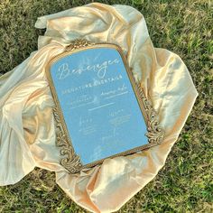 a blue sign sitting on top of a lush green field next to a yellow blanket