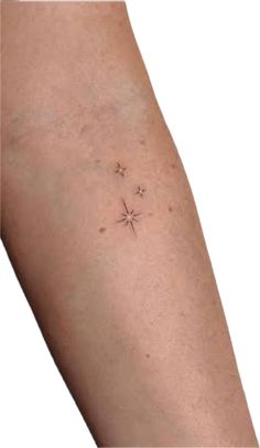 a small star tattoo on the left side of the arm, with two smaller stars above it