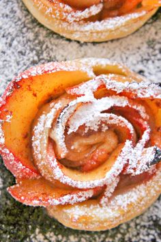 two pastries covered in powdered sugar sit next to each other