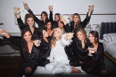 a group of women in black robes holding up wine glasses and posing for the camera