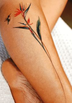 a woman's legs with tattoos on them and flowers painted on the leg area