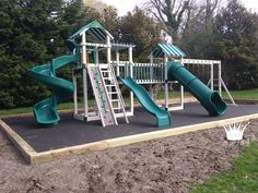 a green and white play set in the middle of a field with trees behind it