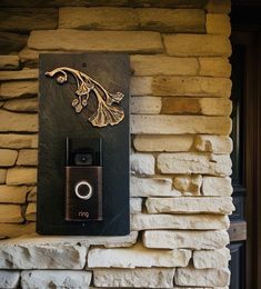 a camera mounted to the side of a stone wall next to a brick building with a plaque on it