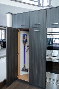 an open cabinet with a blue vacuum in it's center and the door opened