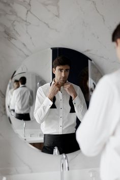 a man standing in front of a bathroom mirror brushing his teeth and looking at himself in the mirror