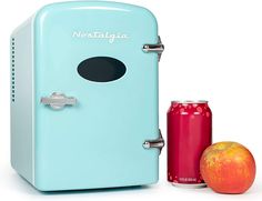 a blue refrigerator next to an apple and a red can