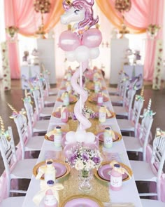 a long table with pink and gold plates, unicorn balloons and other decorations on it