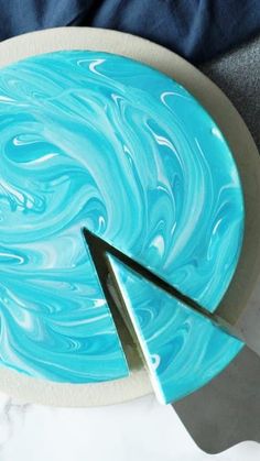 a cake with blue swirled icing on it and a pair of scissors next to it