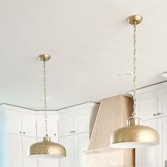 a kitchen with two pendant lights hanging from the ceiling