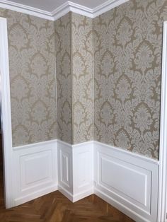 the corner of a room with wallpaper and wood flooring is shown in this image