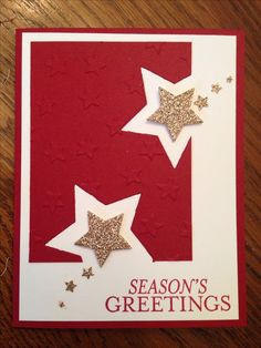 a red and white card with gold stars on the bottom, says season's greetings