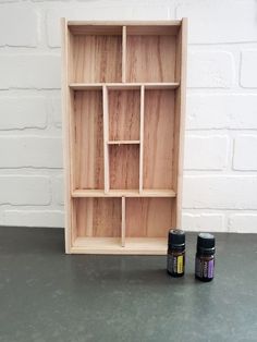 two bottles sit next to each other in front of a wooden shelf with three compartments