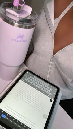 a woman sitting at a desk with a laptop computer and a pink coffee cup in front of her