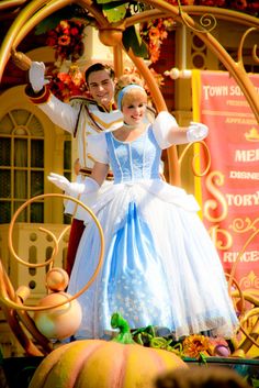 a man and woman dressed up as disney characters in front of a pumpkin carriage at disneyland world